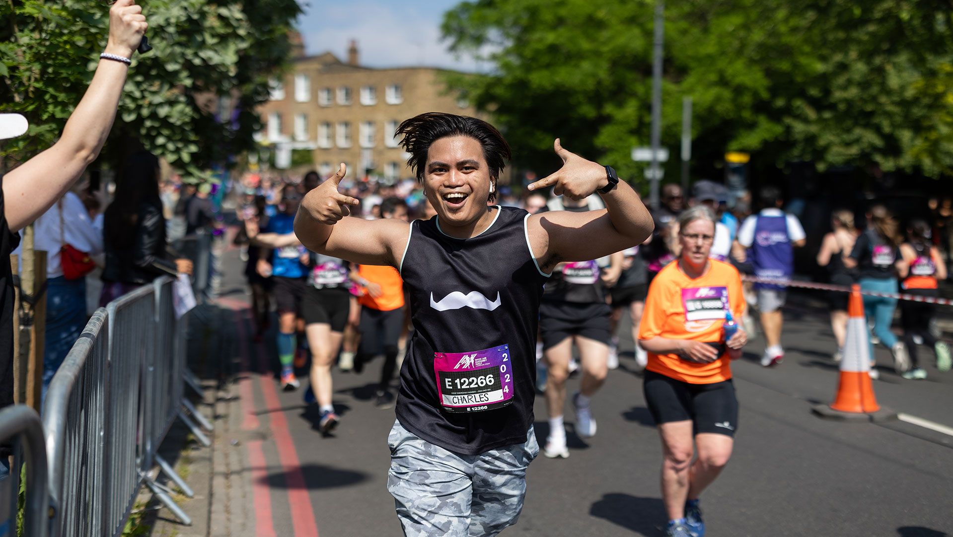 Photo of a man at a marathon triumphantly gesturing toward camera.