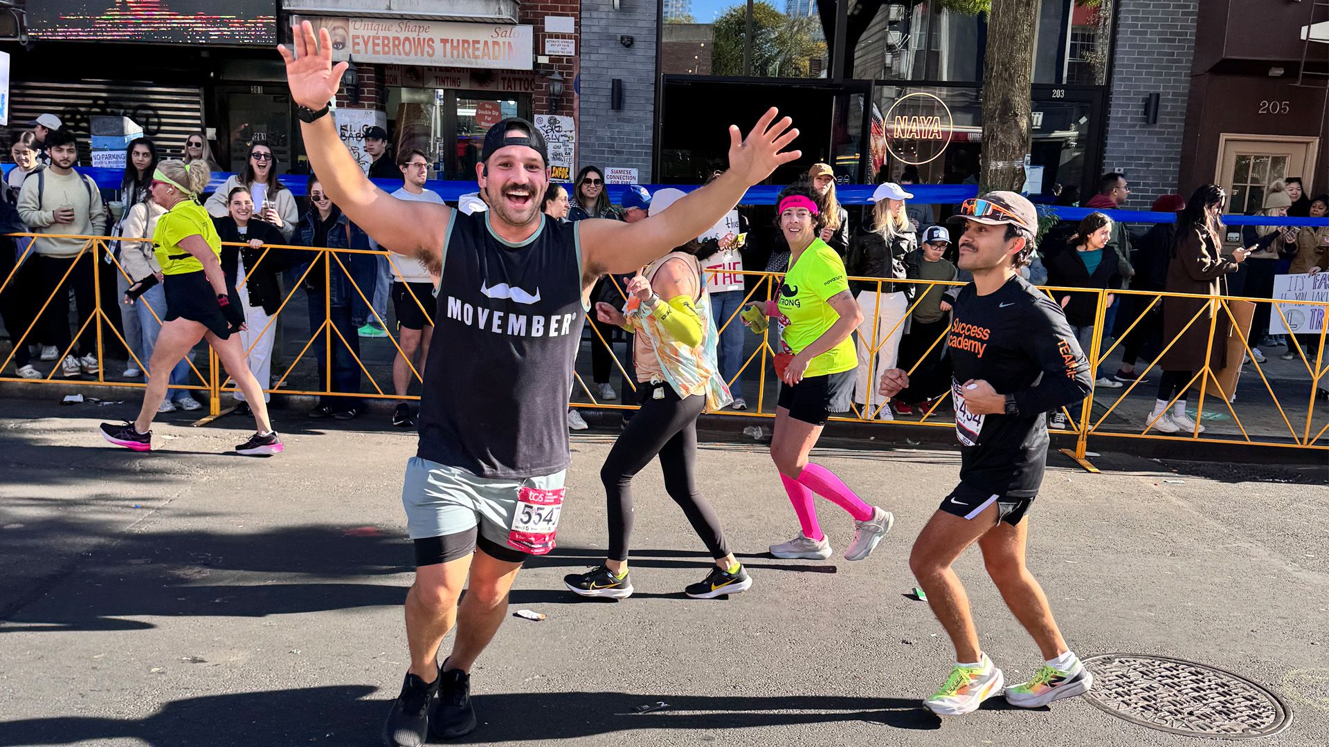 Runner competing in New York City Marathon, triumphantly running past camera.