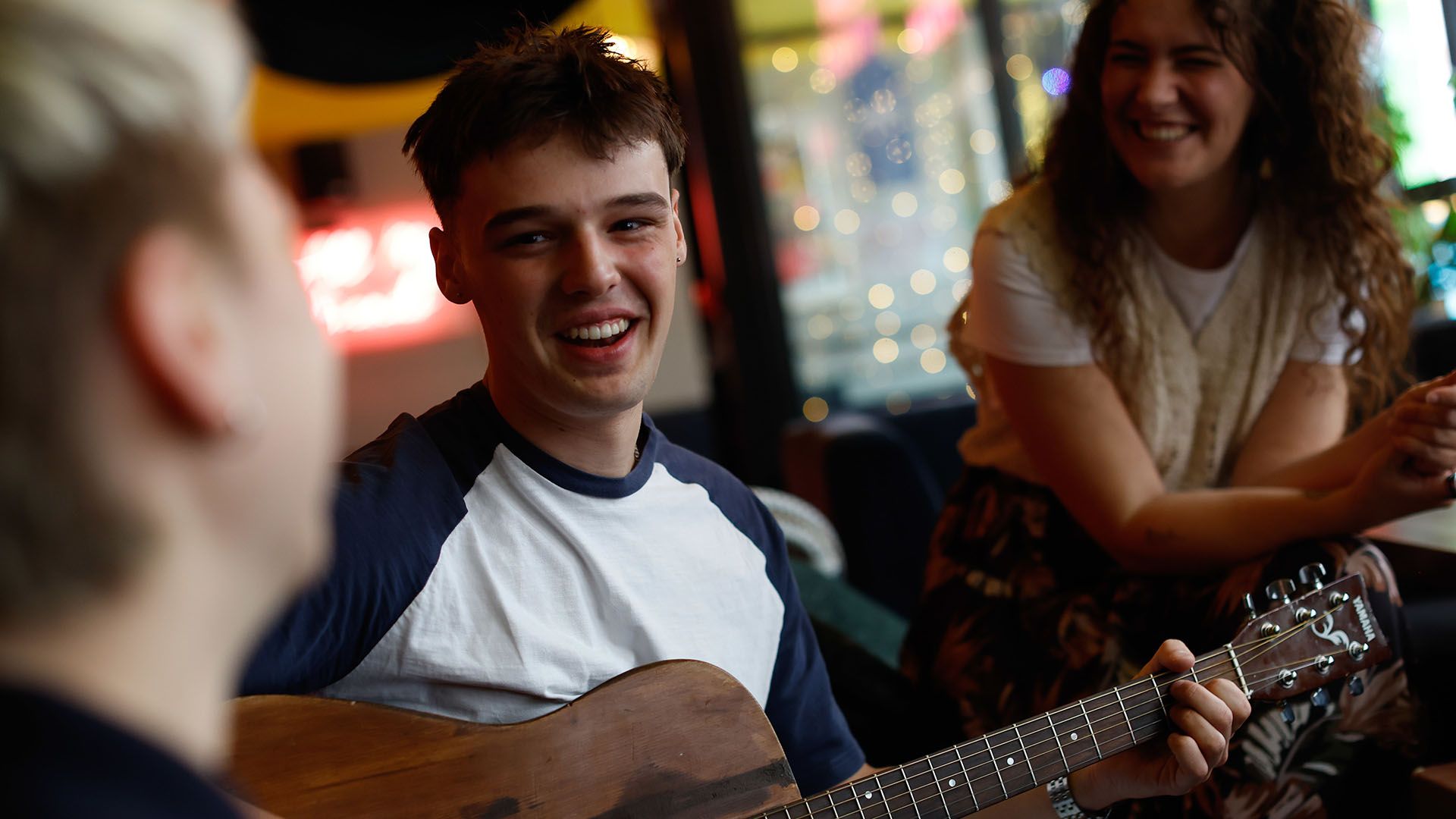 Stock photo of a young man joyfully playing an acoustic guitar with his family