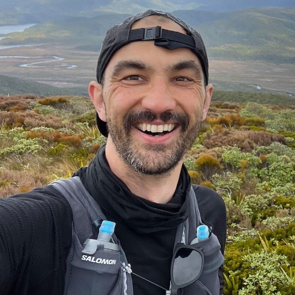 Photo of a man in outdoor active-wear, smiling to camera.