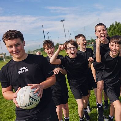 A photo of group of six young men at training holding a football and laughing together.