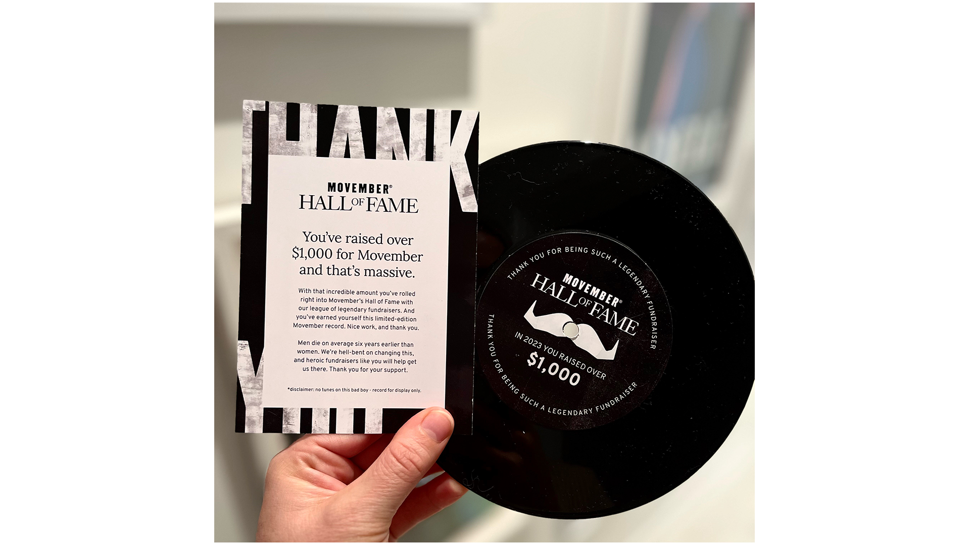 A photo of a Movember-branded vinyl record which says 'Welcome to the Hall of Fame, Movember 2022'