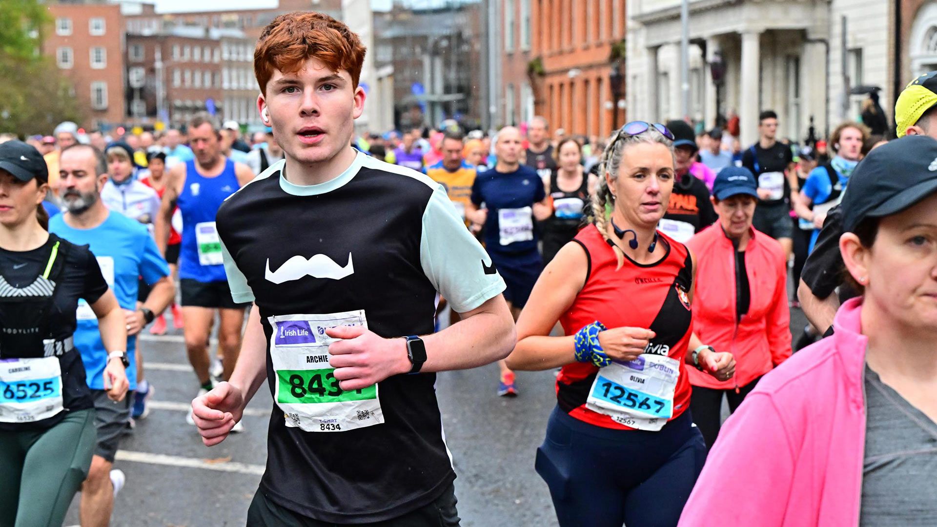 Photo of marathon runners in the streets of Dublin, wearing Movember-branded attire.