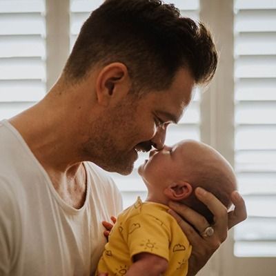 Photo of a father lovingly holding an infant.