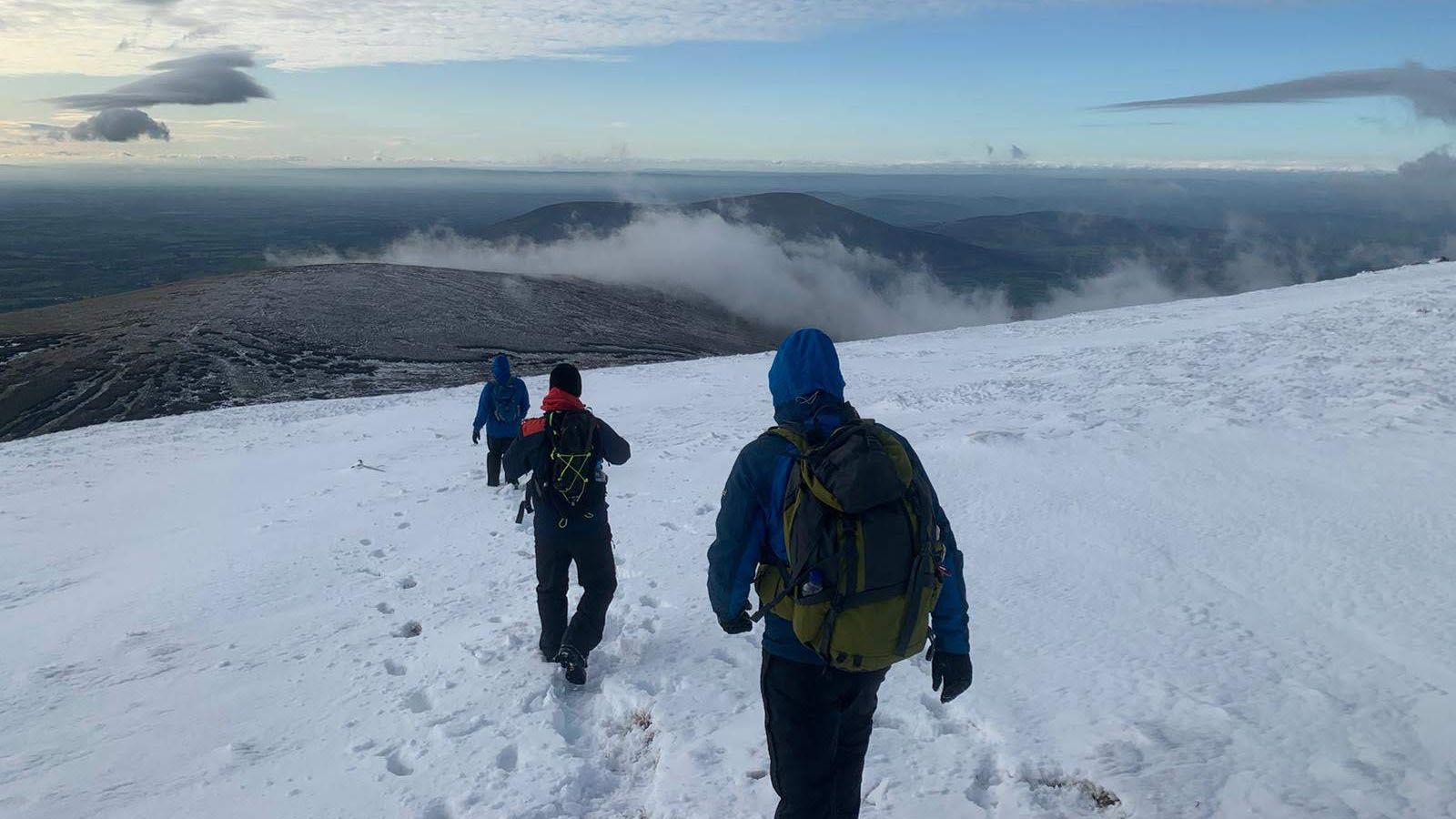 Mountaineers hiking over mountainous snow field.