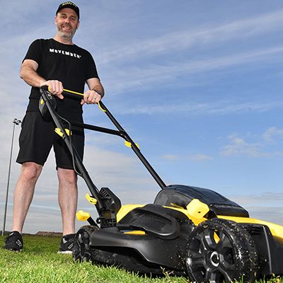 Photo of a man pushing a lawnmower