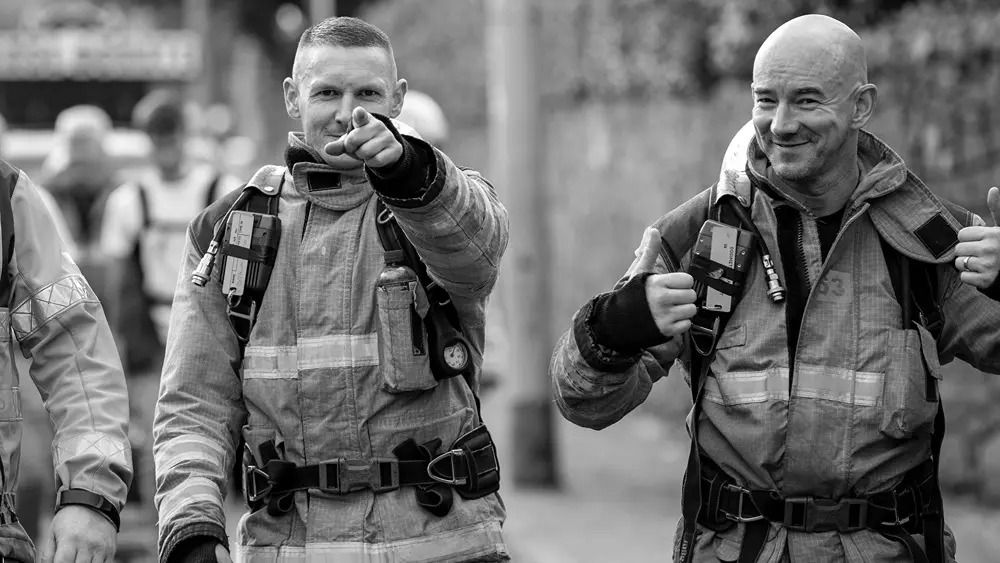 2 men pointing at camera in their emergency services uniform