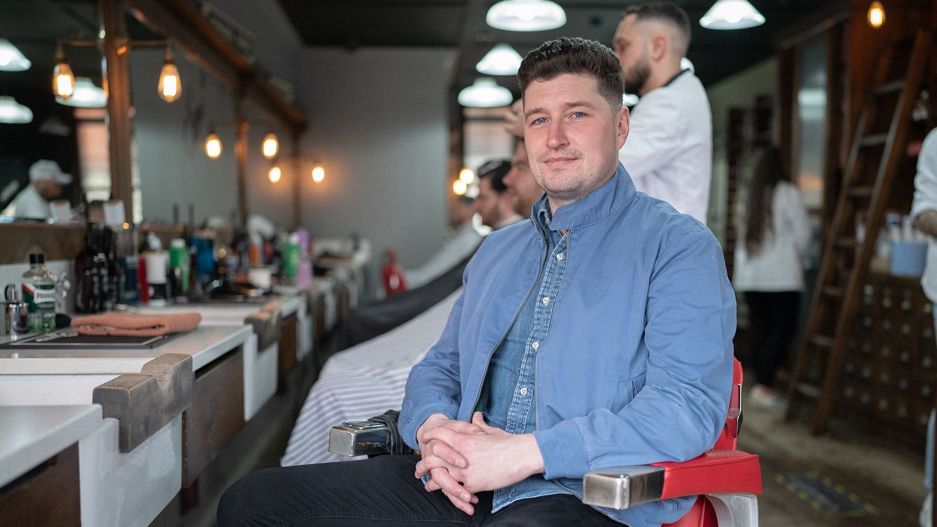 David sat in a chair at a barber smiling at camera
