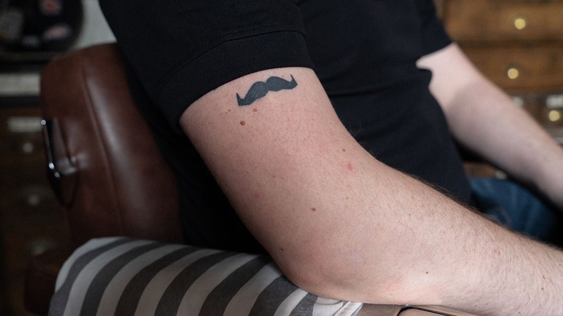 Tattoo of a moustache on Aarons arm