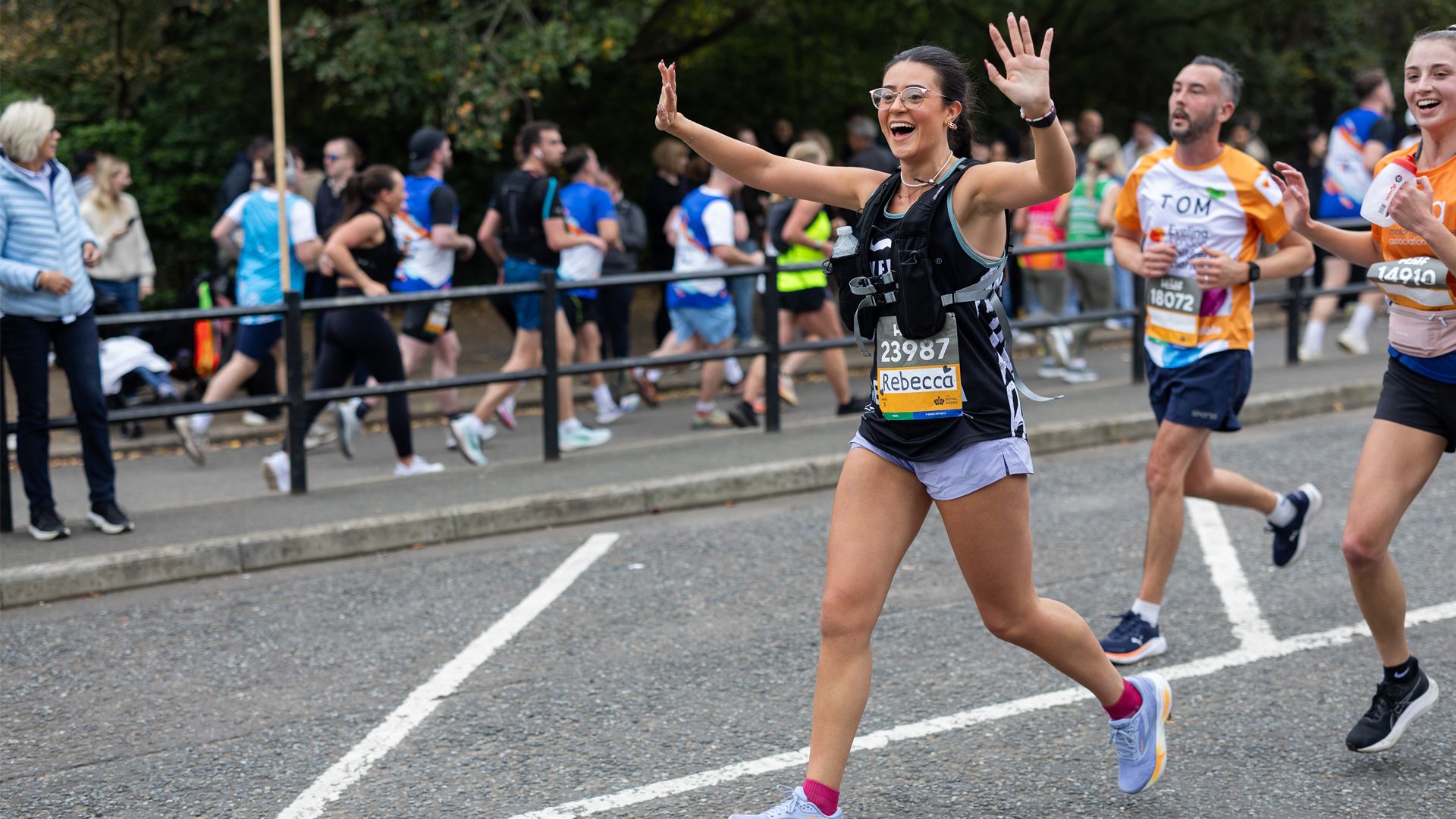 Movember runner waving to a crowd at a race.