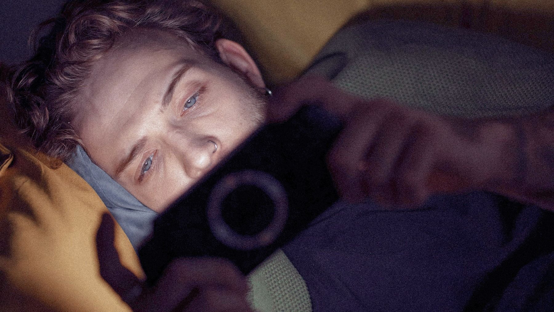 A young man staring at his phone screen