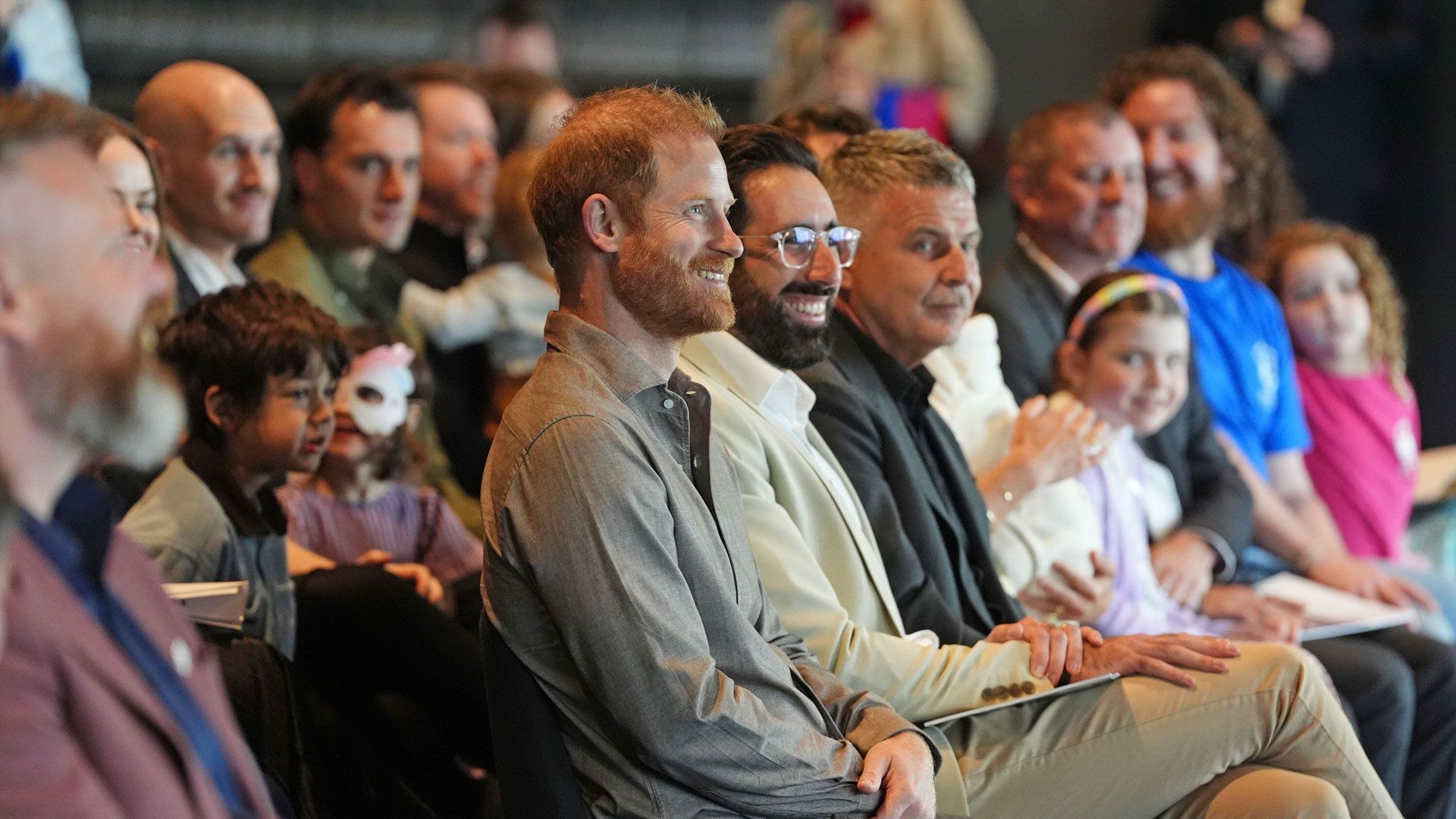 Prince Harry smiling in seats with Movember reps